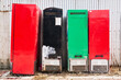 Close-up view of multicolored old and rusty refrigerators placed in a row next to a corrugated metal wall, seen along a road in the Philippines, Asia 