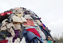 Large Pile Stack Of Textile Fabric Clothes And Shoes. Concept Of Recycling, Up Cycling, Awareness To Global Climate Change, Fashion Industry Pollution, Sustainability, Reuse Of Garment.
