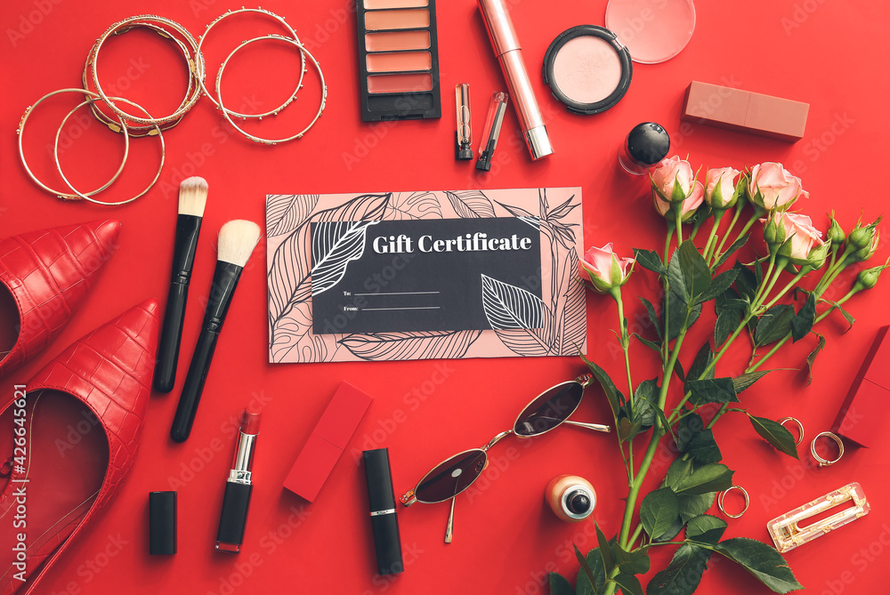 Gift certificate, decorative cosmetics and female accessories on color background