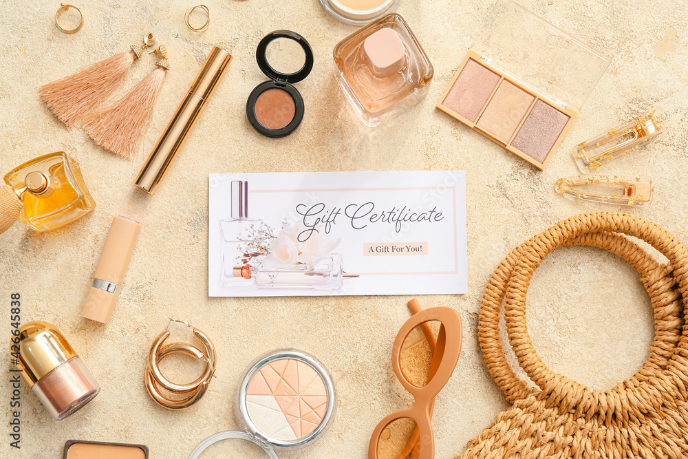 Gift certificate, decorative cosmetics and female accessories on color background