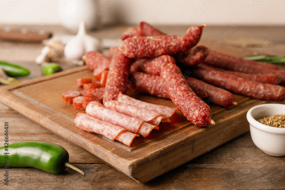 Cutting board with tasty sausages on wooden background