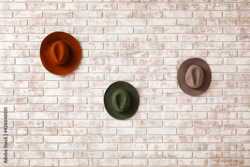 Stylish hats on light brick background