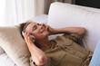 © Wavebreak Media - Happy caucasian senior woman in living room lying on couch wearing headphones and smiling
