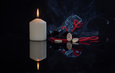 Wall Mural - Odal rune, a burning candle, an old leather bag for Scandinavian runes on a dark background in a haze with a mirror image of the rune. Duality in the meaning of the rune, depending on its position.