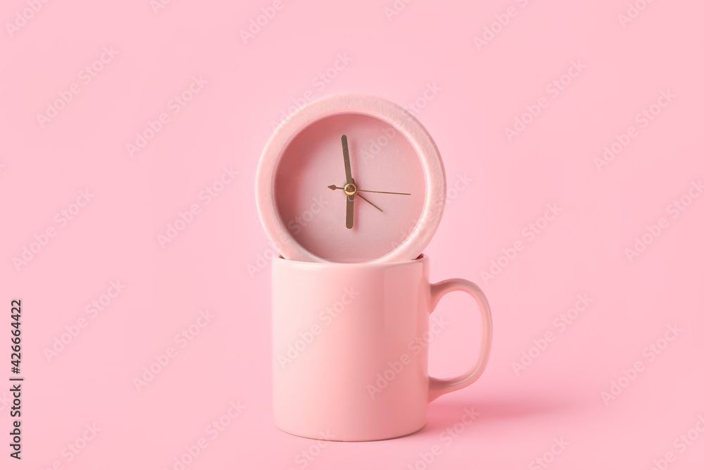 Alarm clock and cup on color background