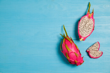 Wall Mural - Pitaya - an exotic low-calorie nutrient-dense fruit with high amount of fiber and magnesium. Whole and halved dragon fruit, visible pulp texture on blue wood background. Close up, copy space, top view