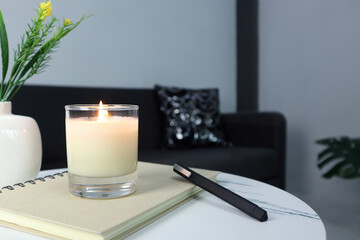 Wall Mural - luxury aroma lighting aromatic scented candle glass displayed on white marble table to creat romantic and relax ambient on valentine day with background of grey sofa in living room