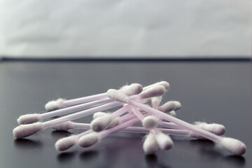 White cotton swabs on a dark background. Side view. The concept of using in cosmetic procedures, harm to the ears.