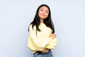 Teenager Chinese woman isolated on blue background with arms crossed and looking forward