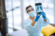 © maxbelchenko - Young nurse in visor and protective gloves examines an X-ray  lung. Pneumonia.X-rays of light. Fluorography. Covid-2019.