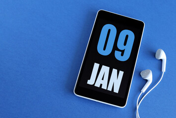 January 9. 9 st day of the month, calendar date. Smartphone and white headphones on a blue background. Place for your text. Winter month, day of the year concept.