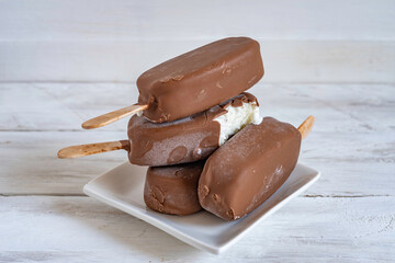 Wall Mural - Homemade Chocolate Covered Ice Cream on white wooden background.