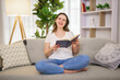 © Louis-Paul Photo - Charming woman reading a book sitting on a sofa in a living room