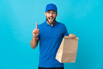 Wall Mural - Delivery man with beard isolated on blue background pointing up a great idea