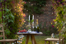 Champagne and red currants on table with candles in idyllic garden