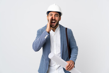 Canvas Print - Young architect man with helmet and holding blueprints isolated on white background shouting with mouth wide open