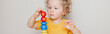 © anoushkatoronto - Cute baby toddler playing with learning toy pyramid stacking blocks at home or kindergarten. Early age Montessori education. Kids hand brain fun development activity. Web banner header.