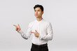 Serious-looking sulking thoughtful asian guy in formal outfit, look and pointing left thinking, pondering, making important decision, ready pick variant, standing pensive white background