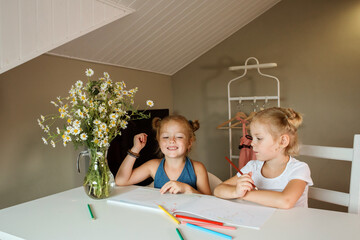 Two little sisters spending time at home painting in the album.