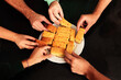© Ri Fotoproducto - Close-up detail of hands taking portions of sweet cake from a white plate on a black table. View from above.