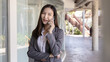 © Puwasit Inyavileart - Young Asian female employee in a gray suit stands under the building of an office building talking on the phone, Talking using a mobile phone, Business communication, Smiling woman in a gray suit.