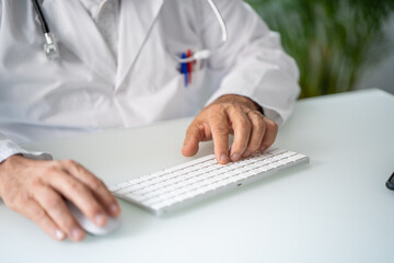 Wall Mural - Close up of a Doctor in white coat working telematically in his office