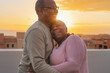 © Alessandro Biascioli - Happy Latin senior couple having romantic moment embracing on rooftop during sunset time - Elderly people love concept