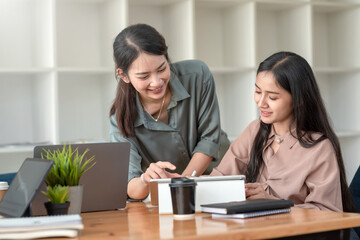 two asian woman are happy to work together using tablet at the office.
