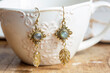 brass labradorite stone earrings on white cup background