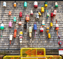 Vintage Lobster Buoys Hanging On A Weathered Wall With Yellow Traps On The Bottom