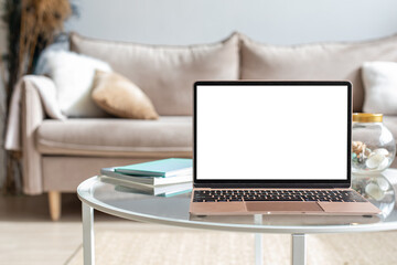 Wall Mural - Laptop with blank white screen on the desk, mock up. Personal laptop computer on wood table in living room with modern interior.