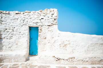 The narrow streets of the island with blue balconies, stairs and flowers in Greece.