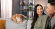 © VAKSMANV - Close up of joyful young Asian married couple sitting on sofa in room at home and chatting while woman caring cute cat. Animal pet lover, family member, boyfriend and girlfriend, pet adoption concept