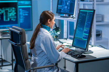 Female microelectronics engineer works in a scientific laboratory on computing systems and microprocessors. Professional electronic factory worker is testing the motherboard and coding the firmware.