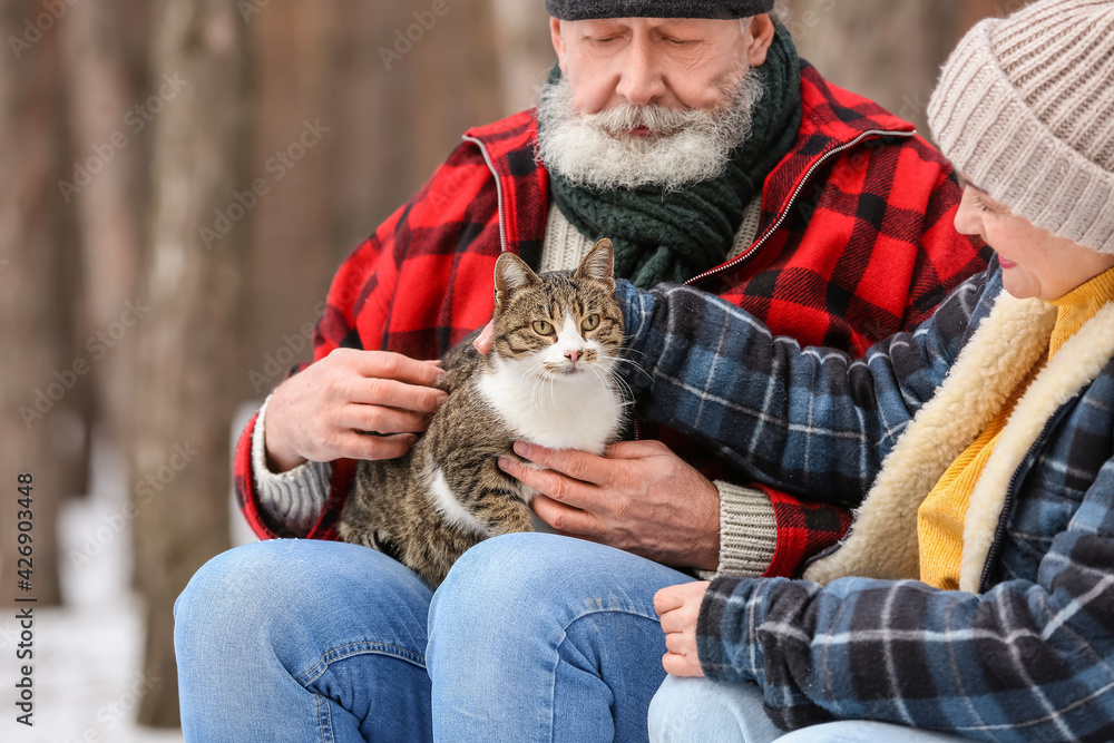 Happy mature couple with cat in forest on winter day