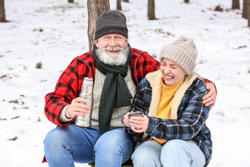 Poster - Happy mature couple drinking hot tea in forest on winter day