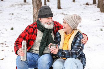 Poster - Happy mature couple drinking hot tea in forest on winter day