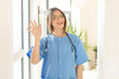 © kues1 - pretty nurse smiling happily and cheerfully, waving hand, welcoming and greeting you, or saying goodbye