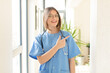 © kues1 - pretty nurse looking excited and surprised pointing to the side and upwards to copy space