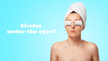 Tea Bags Against Circles Under The Eyes. A Girl With Tea Bags In Her Eyes With A Towel On Her Head On A Blue Background.