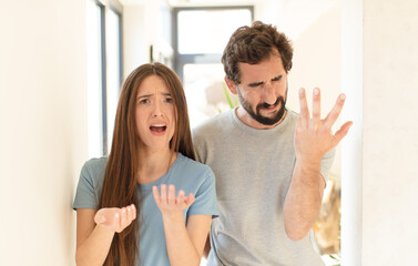 Wall Mural - young couple looking desperate and frustrated, stressed, unhappy and annoyed, shouting and screaming