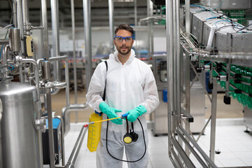 Wall Mural - Exterminator in industrial plant spraying pesticide with sprayer. Disinfection of the factory due to the coronavirus epidemic.