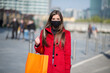 Masked woman carrying shopping bags while wearing a mask, covid and coronavirus concept