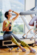 © shevtsovy - attractive fitness woman tired after workout drinks protein shake.Sexy fitness model resting after workout exercises in gym. fitness exhausted female with protein shaker.