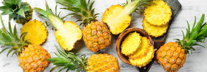 Pineapple collection. Whole and sliced pineapple, on a white wooden background. Top view. Free space for text.