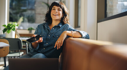 Wall Mural - Happy freelancer sitting on sofa in coworking space