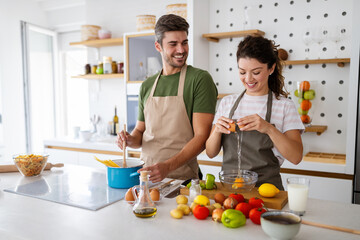 Wall Mural - Happy young couple preparing food in kitchen at home