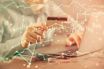 Double exposure of man hands holding a credit card and Forex graph drawing. Stock trading and digital fintech in Internet E-commerce concept.