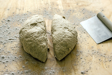 Rye dough for baking bread and knife for cutting dough on wooden background, close-up. Authentic hobby home baking