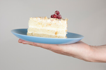 Poster - Hand serve a piece of soft cream cake on white background. Copy space concept.